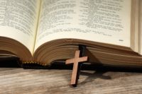 Bible and cross on wooden table, closeup. Religion of Christiani