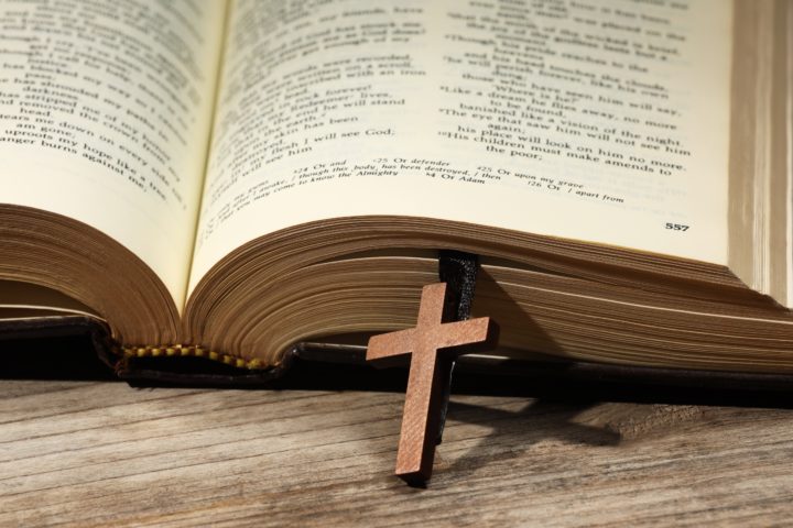 Bible and cross on wooden table, closeup. Religion of Christiani