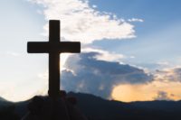 cropped-hand-holding-religious-cross-against-sky